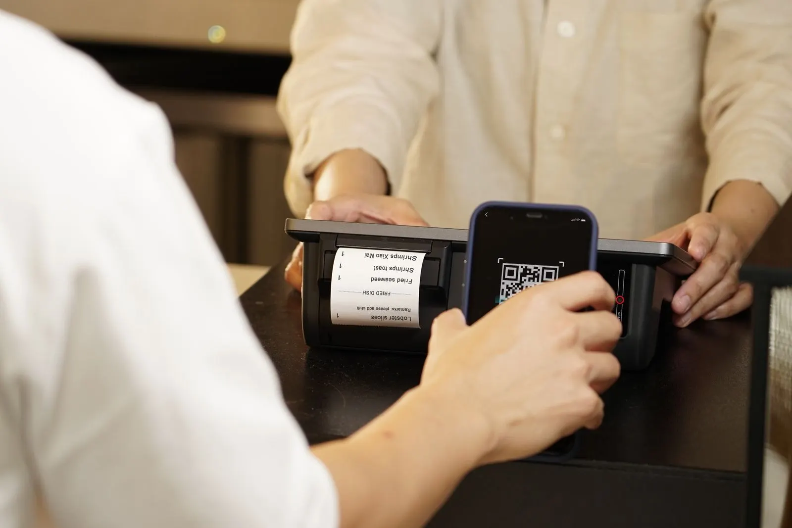 Gros plan sur un smartphone scannant un QR-code posé sur une table